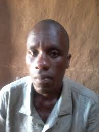 Man in blue shirt in front of earthen wall